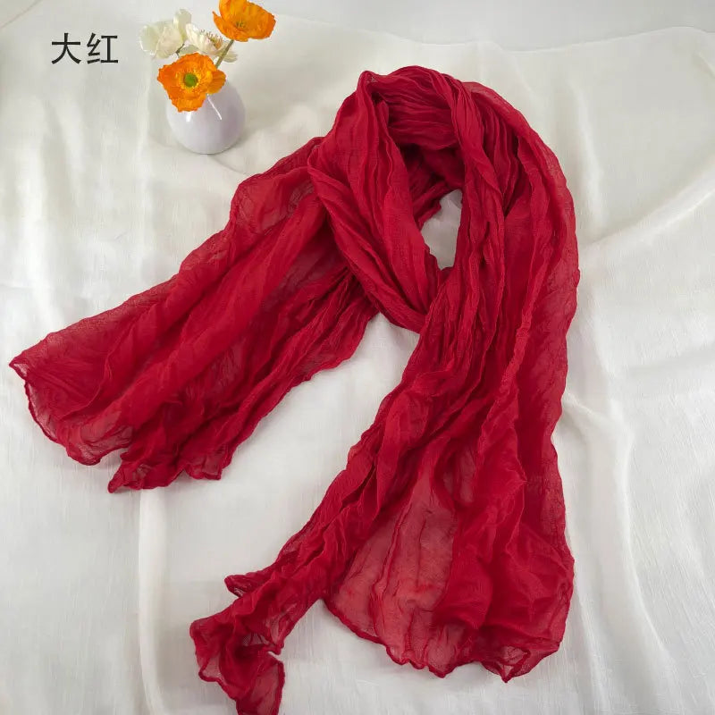 Écharpe en coton et lin plissé présentant une mousseline de chiffon rouge vif et fluide, avec une texture légère et douce et des plis froncés délicats