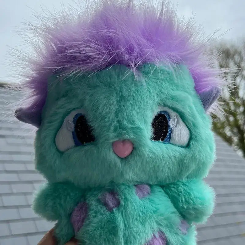 The bibble plush toy is a cute stuffed anime doll made of teal plush material with spiky purple fur, blue embroidered eyes, and a pink nose.