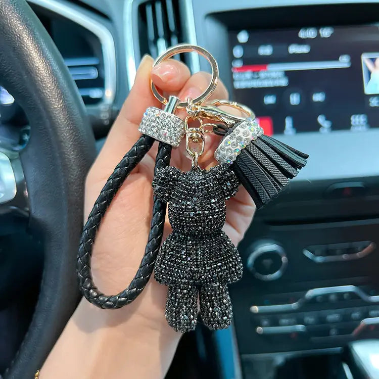 Black rhinestone-encrusted bear-shaped keychain with braided leather strap and crystal-adorned tassel.