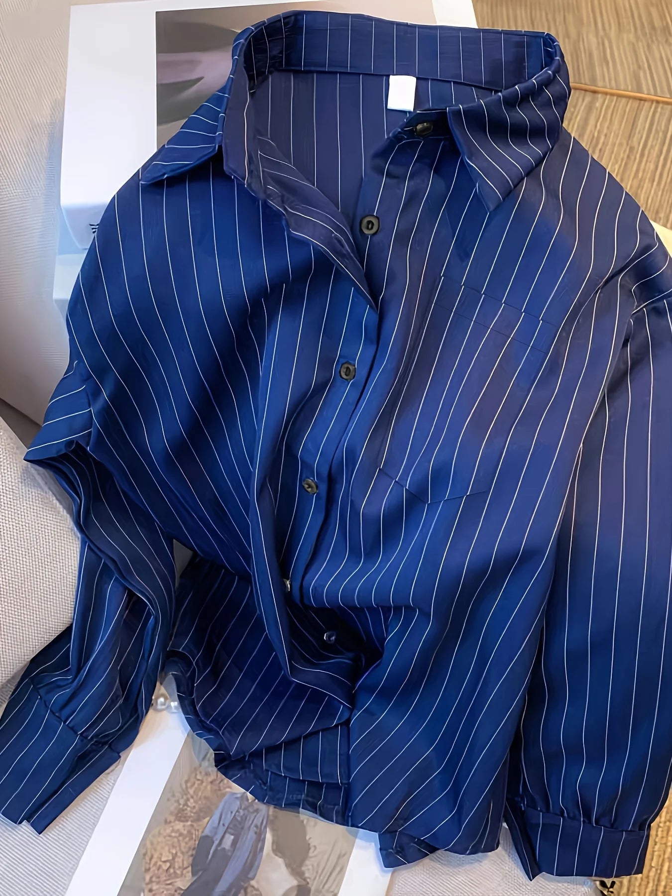Une chemise à manches longues rayée bleu marine pour femmes, présentant des fines rayures verticales blanches et un col classique, idéale pour un esprit de conception printanière.