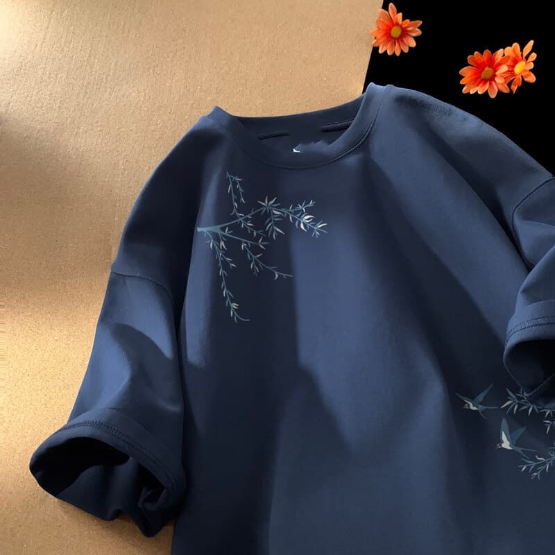 Camiseta de algodón oversize azul marino con delicadas ramas bordadas en blanco y pájaros en la parte delantera.