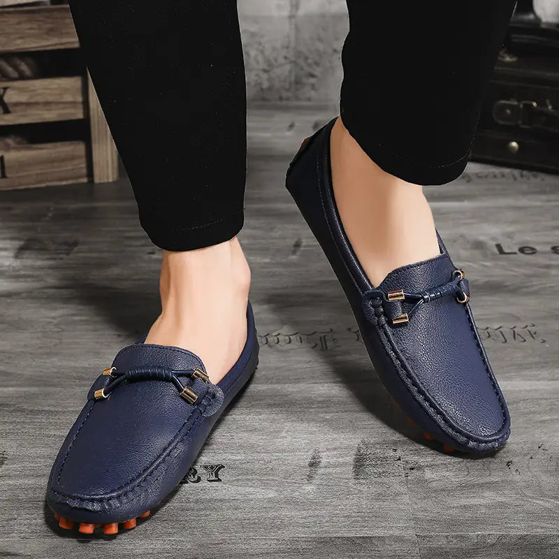 Chaussures à enfiler habillées en cuir bleu marine pour hommes, se portant sans effort avec des chaussures décontractées, avec des accents métalliques ton or et des semelles en caoutchouc orange.