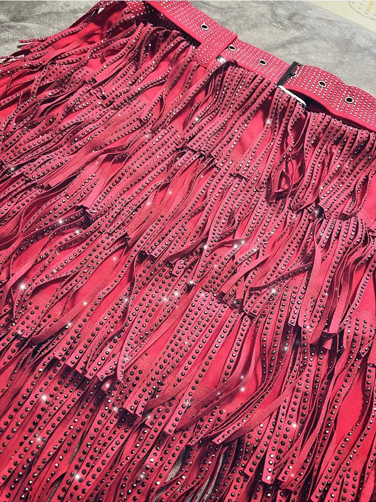Mini-jupe taille haute rouge vif à franges en strass, avec des bandes en cuir en cascade ornées de rangées de clous noirs scintillants.