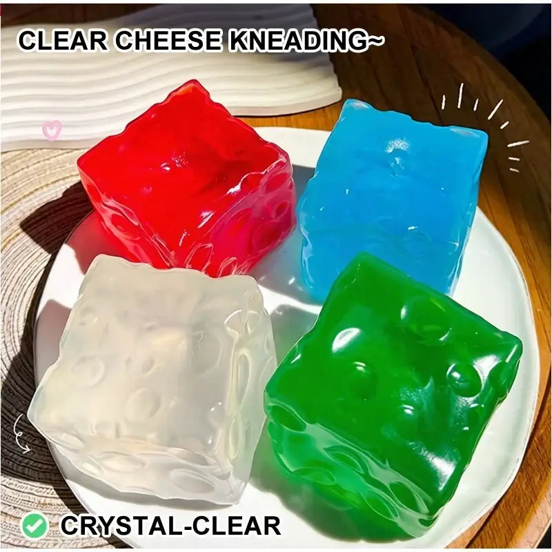 Ein farbenfrohes Vaseline-Käse-Quetschspielzeug, das transluzente, geleeartige Würfel zeigt, geformt wie Käse, mit eingebetteten Öffnungen und einer glänzenden Oberfläche, von vorn betrachtet