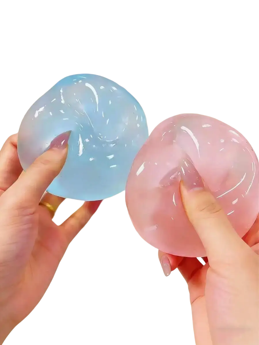 Two translucent gel-like moldable slow rebound stress balls in light blue and pink held against a beach backdrop