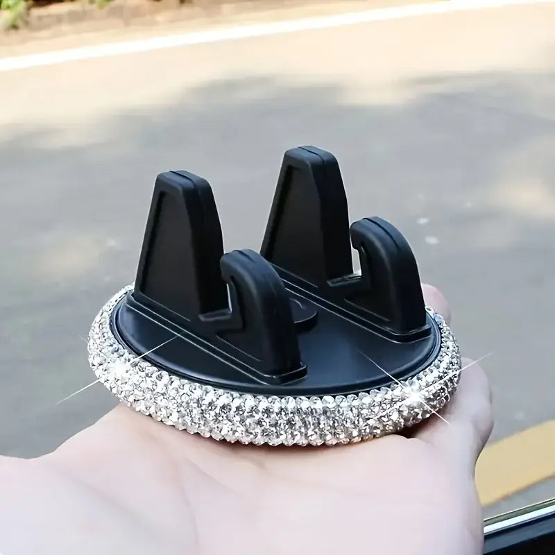 Soporte negro para teléfono de automóvil con ventilación, con ribete de pedrería brillante en color plateado que realza su diseño elegante.
