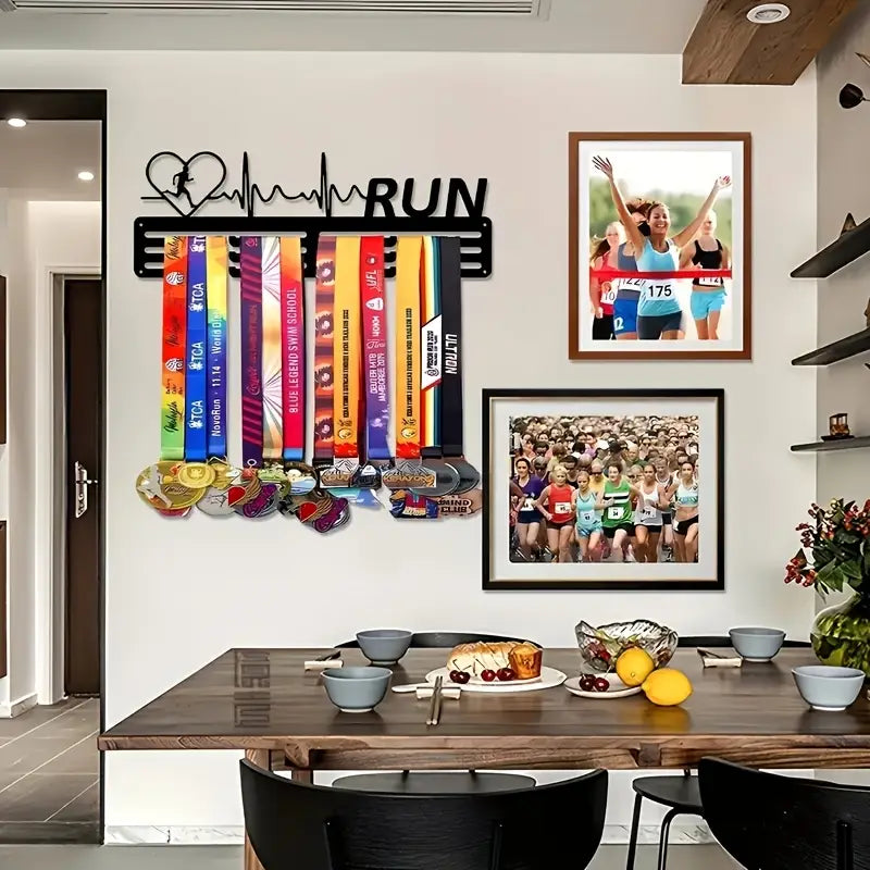 Black metal running medal display rack with heart-shaped silhouette and run lettering mounted on wall holding colorful ribbons and medals.