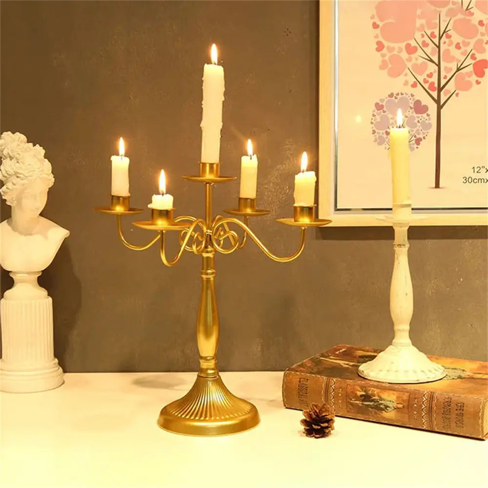 grande candelabre en métal doré avec cinq bougies blanches allumées, servant d’élégantes décorations de table, modernes, pour une décoration européenne, dans un cadre de mariage d’hôtel.