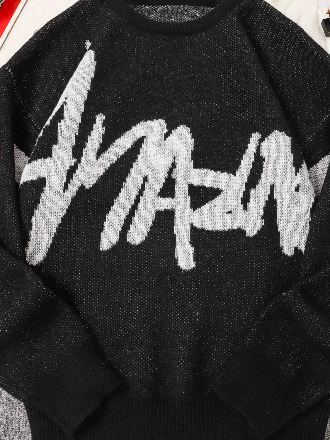 Men black knit sweater featuring a bold white graffiti style amazing graphic across the chest.