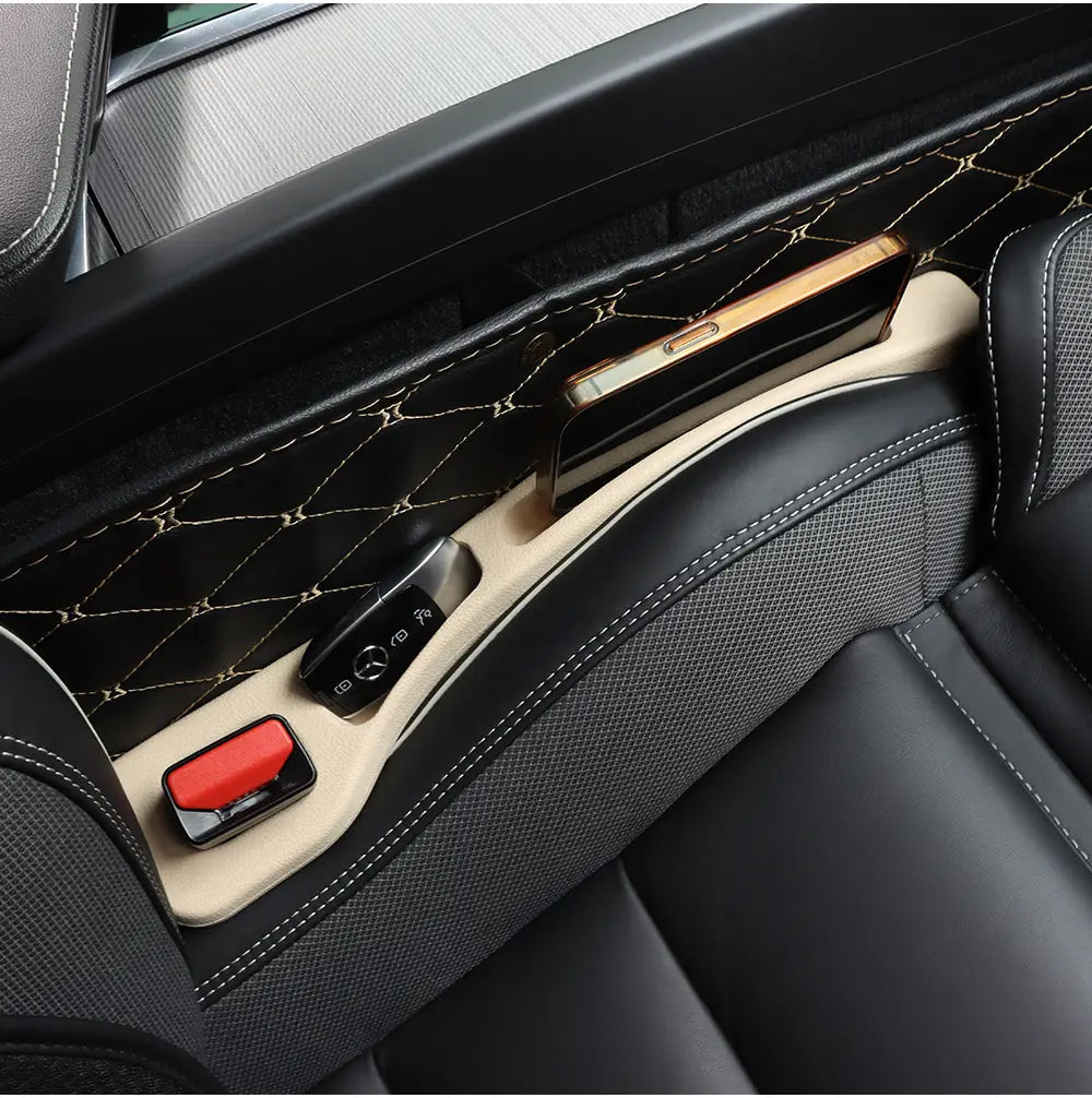 Comblement d’interstice de siège en cuir beige, avec bordure cousue en losanges noires, maintenant un smartphone doré pour les modèles de la classe AMG GLC, vu depuis le dessus