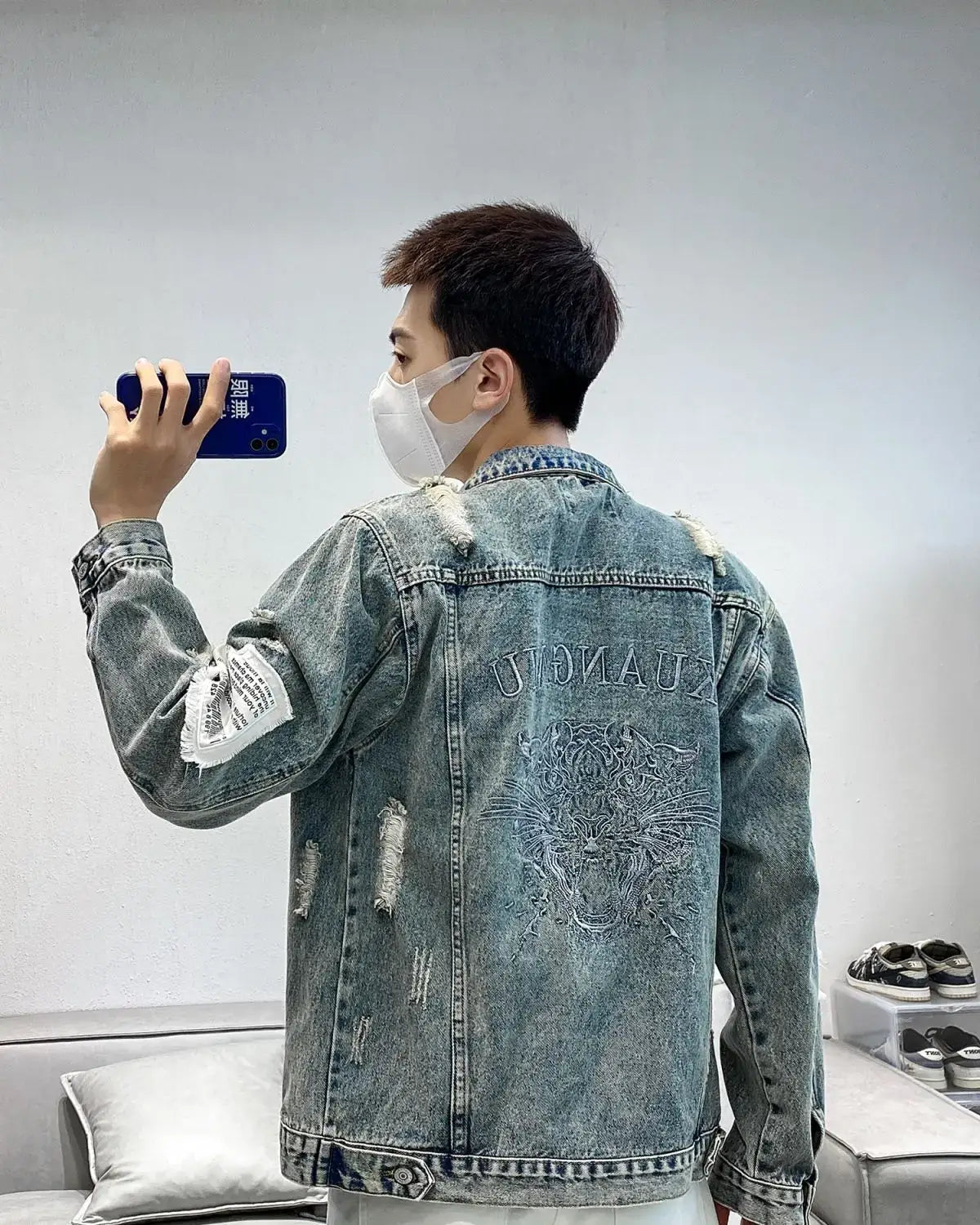 Men embroidered tiger denim jacket in faded blue distressed denim featuring an embroidered tiger design and the word zhuang stitched above on the back side.