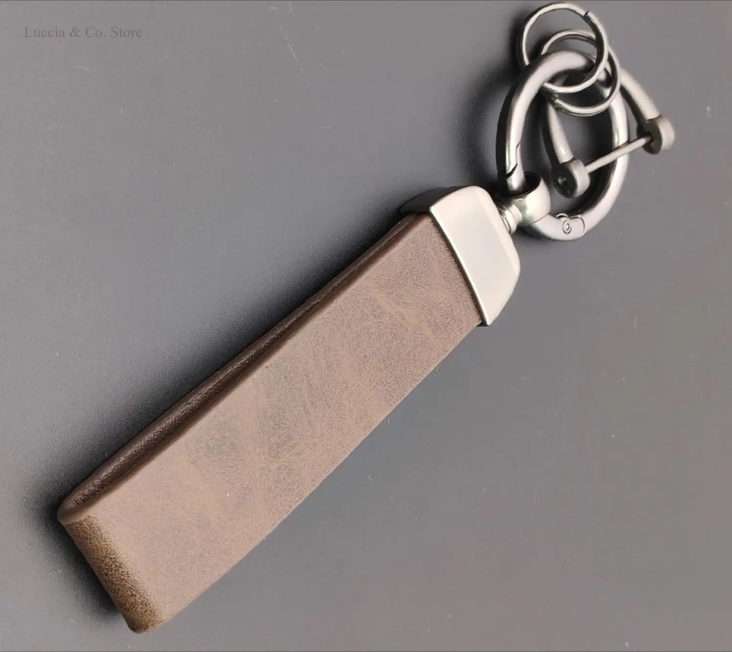 Brown leather custom logo car keychain with silver-toned metal hardware and carabiner clip for personalized use.