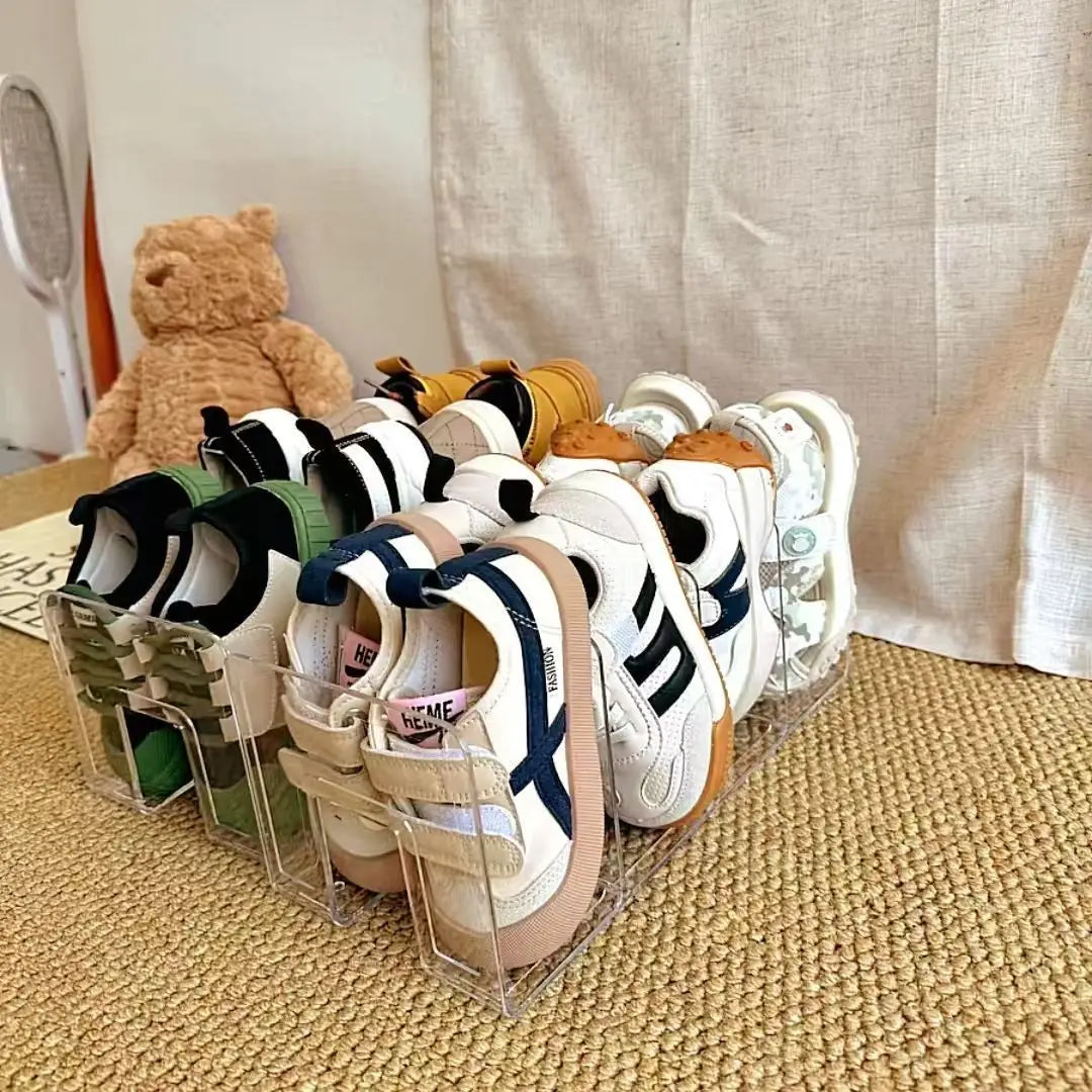durchsichtiger Acryl-Baby-Schuhaufbewahrungsständer zur Anordnung, der mehrere Paar bunter Kindersneaker in verschiedenen Designs enthält.
