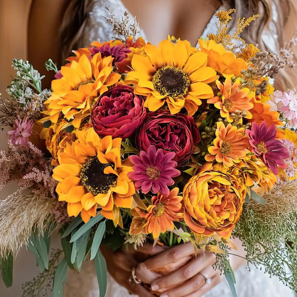 A vibrant autumn-themed artificial flowers bouquet featuring bright yellow sunflowers deep burgundy peonies and orange daisies with dried grasses and greenery for home decoration or to send flowers.