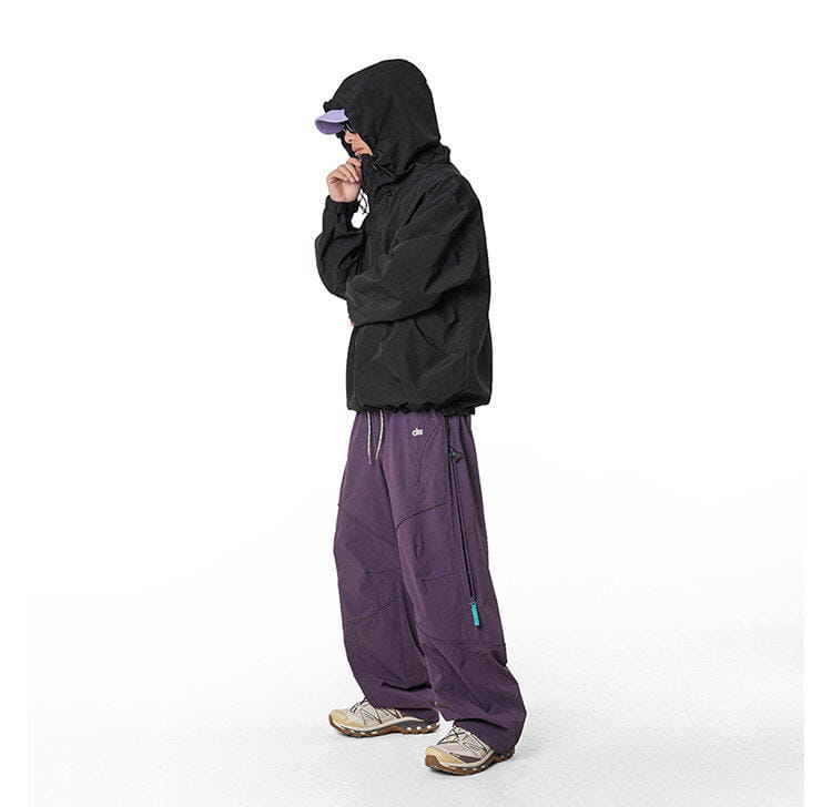 chaqueta con capucha negra con un logotipo sutil en el pecho y cordones ajustables, combinada con pantalones cargo impermeables de senderismo para hombre de secado rápido para actividades al aire libre.