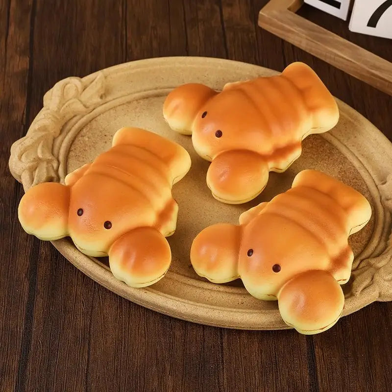 three golden-brown plush slow rising toast fidget toys shaped like fish with small black eyes sit on a rustic wooden plate designed for stress relief and daily stress desktop decoration.