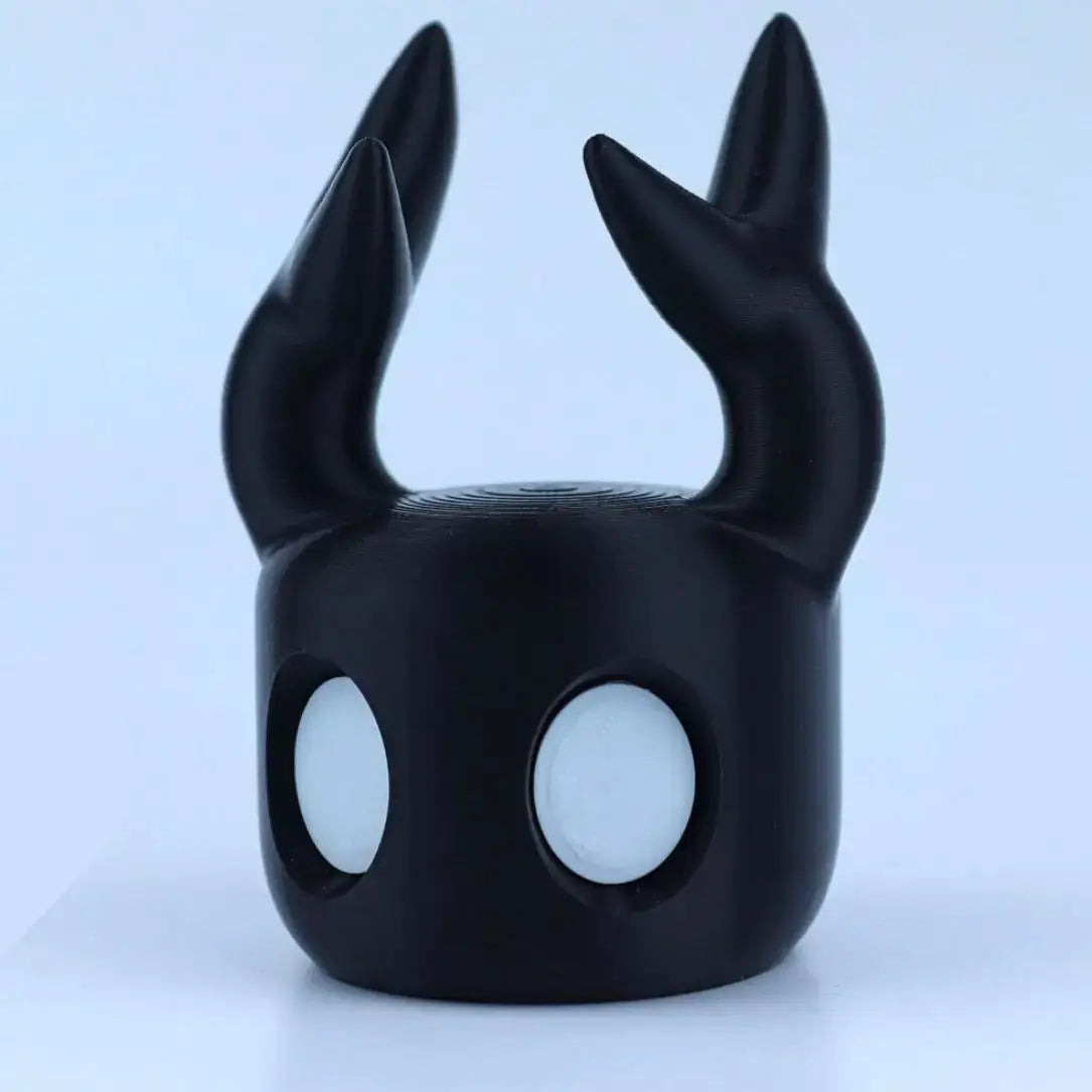 black glossy plastic hollow knight game controller stand for ps5 with two upward-curving horns and large circular eye openings