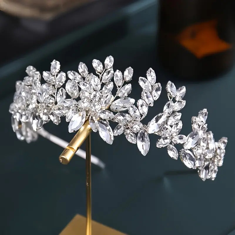 金色調のヘッドバンドを備えた、精緻な葉と花のデザインが施されたきらめくシルバーのクリスタル製フローラル・ブライダル用ティアラヘッドバンド。
