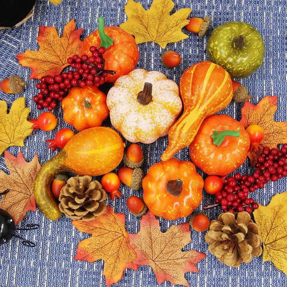 Une collection d’articles de décoration artificielle pour la maison d’automne comprenant des citrouilles texturées en orange et en vert, des bouquets de baies rouges, des feuilles d’érable jaunes, des glands et des pommes de pin, pour des décors d’automne.