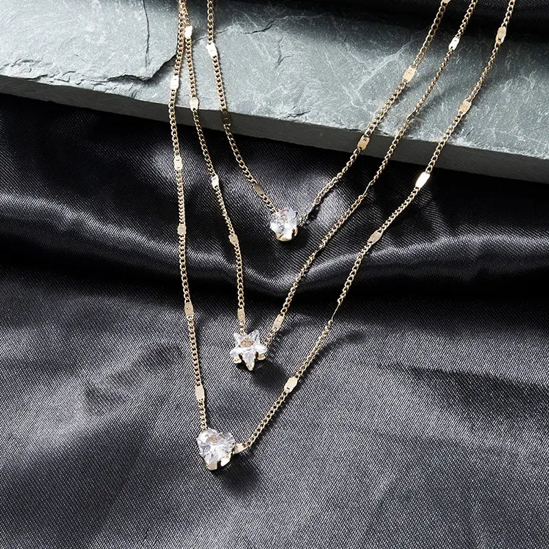 Zircon layered pendant necklace for women featuring gold-toned chains with clear faceted crystal pendants shaped like leaves and a star.