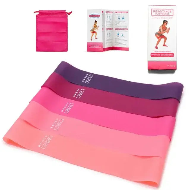 Ensemble de quatre bandes de résistance dégradé rose à violet avec marquage blanc, fabriquées en matériau élastique, présentées avec une pochette de rangement assortie à cordon et l’emballage du produit pour une utilisation en fitness et en pilates.