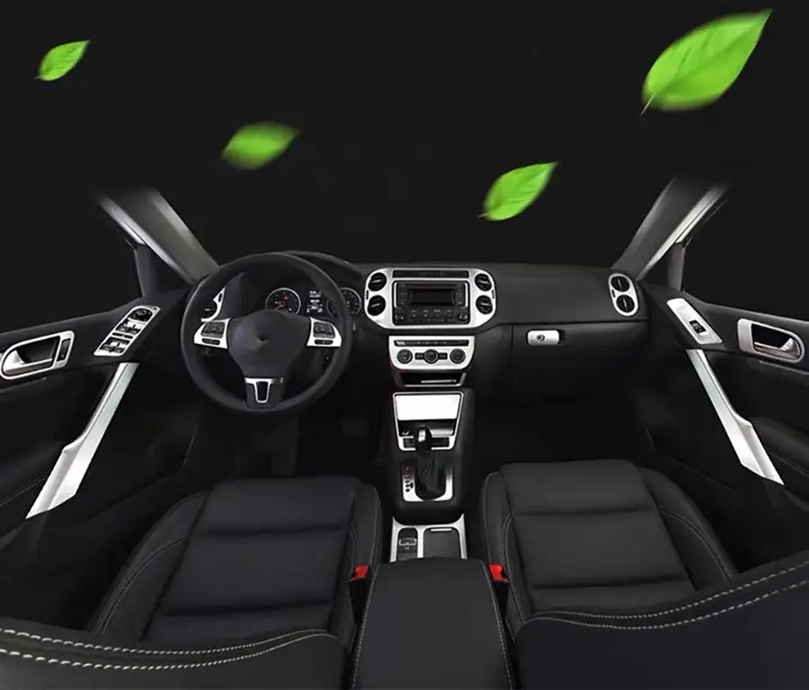 Black leather interior of a Volkswagen Tiguan SUV with silver trim accents and green leaf graphics floating above the dashboard featuring the cup holder panel trim for 2009 to 2017 models.