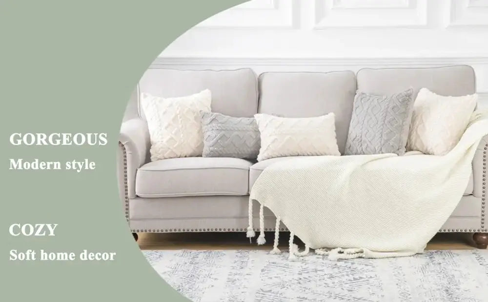 Hellgraues Polstersofa mit geknöpften Rückenkissen und dekorativen einfarbigen quadratischen Kissenbezügen 45x45 cm in aufeinander abgestimmten Creme- und Hellgrautönen, akzentuiert durch eine wollweiße Strickdecke.