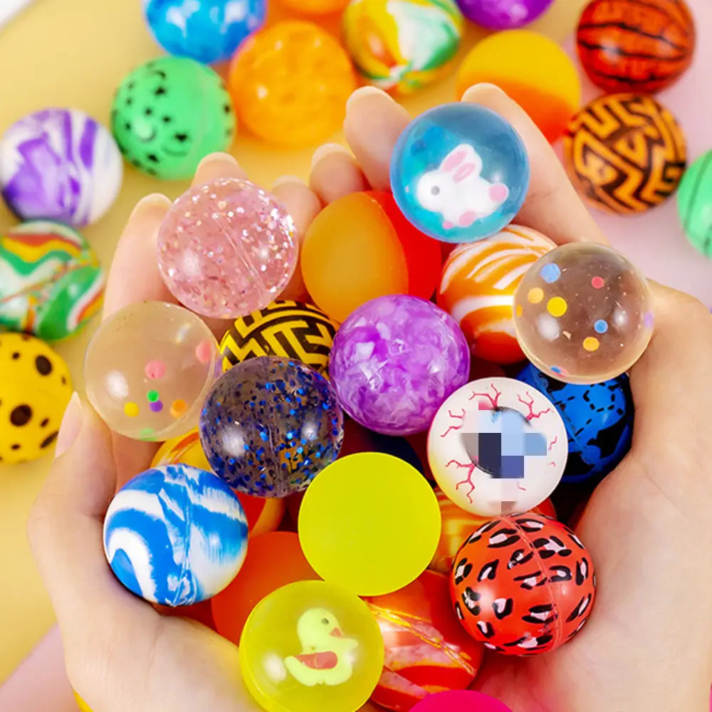 Una mano sostiene un conjunto de coloridas bolas a granel elásticas translúcidas hechas de material blando, con diseños de animales de dibujos animados juguetones para surtido de recuerdos para fiestas.