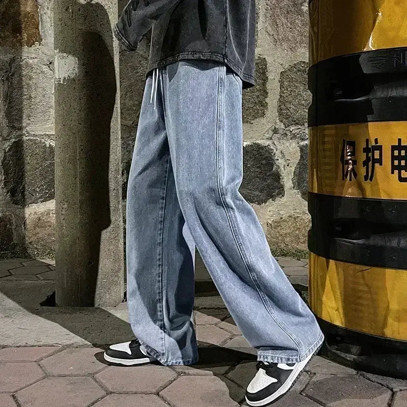 Jeans à jambes larges en denim à lavage clair pour hommes, avec une coupe décontractée et des détails de surpiqûres visibles dans un style streetwear coréen ample.
