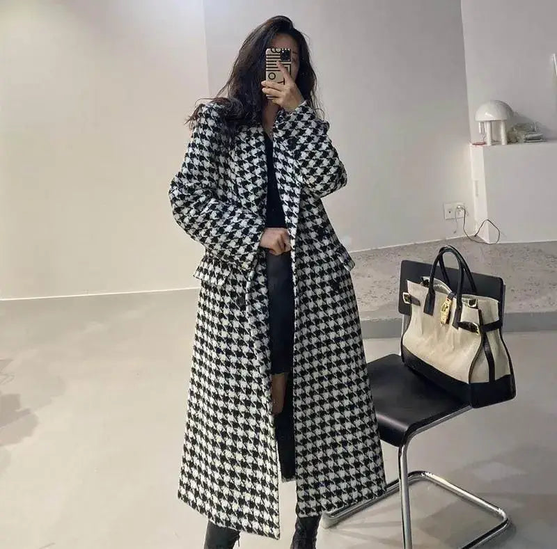 A long black and white houndstooth wool double breasted coat with a structured silhouette and notched lapels.