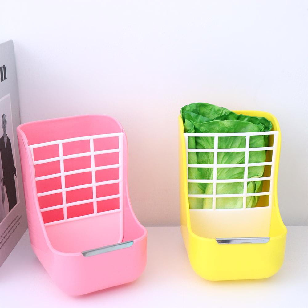 Pink and yellow plastic rabbit hay feeders with white grid fronts and attached food bowls for small animals.