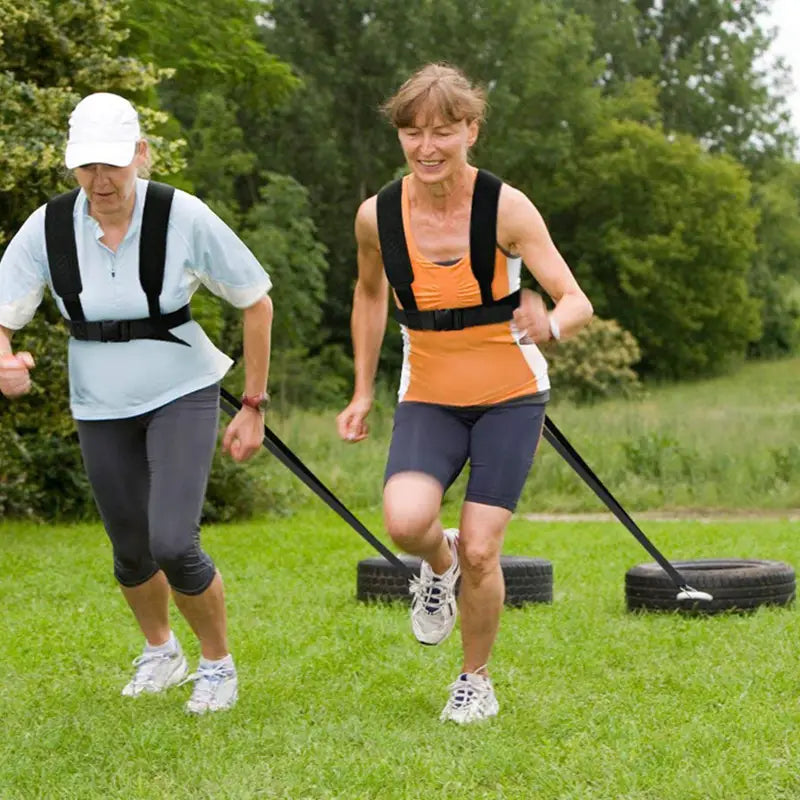 woman wearing a black agility training resistance harness sled pull strap made of durable material during outdoor exercise viewed from the back side