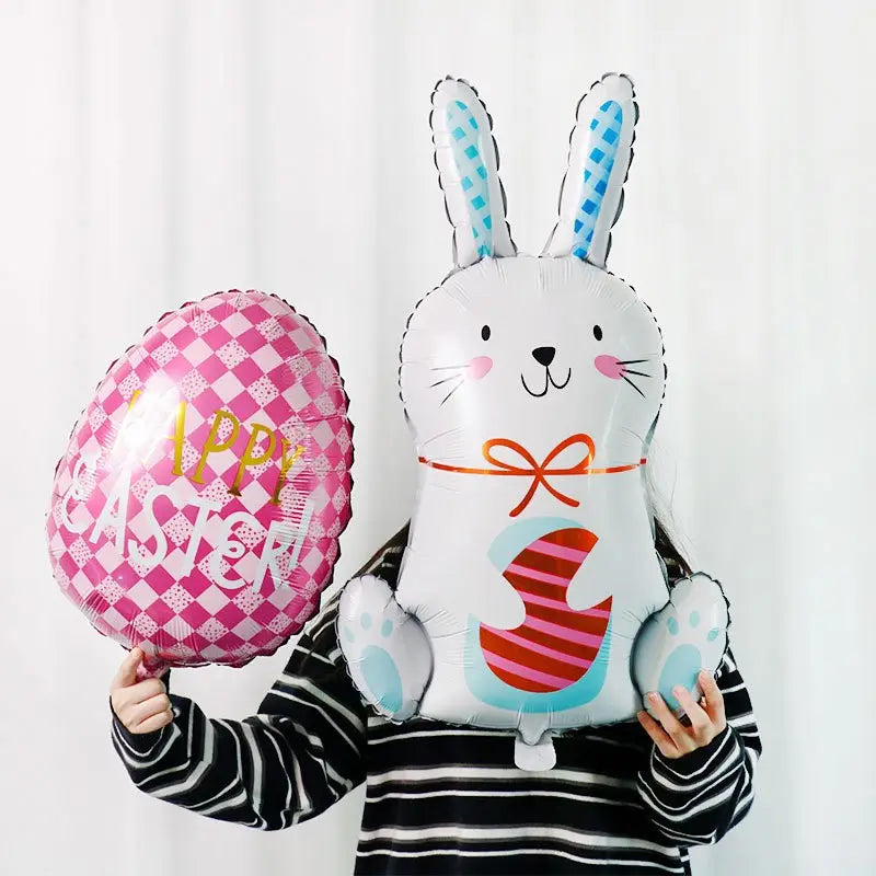 Osterhase-Folienballon-Partydekoration mit einer weißen Hasenform mit blau karrierten Ohren, pinkfarbenen Wangen, einer orangefarbenen Fliege und einem roten sowie pinkfarben gestreiften Eidesign auf dem Bauch.
