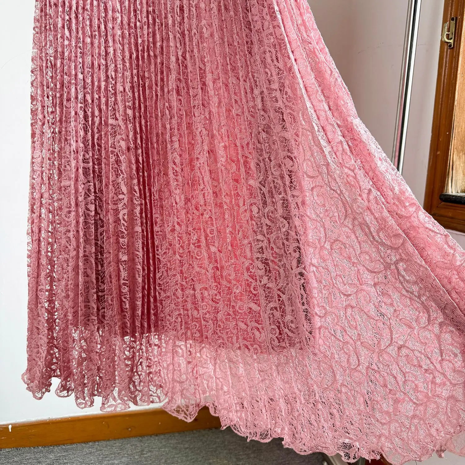 A delicate pink lace high waist pleated midi skirt featuring intricate floral patterns and a flowing layered hem for y2k streetwear.