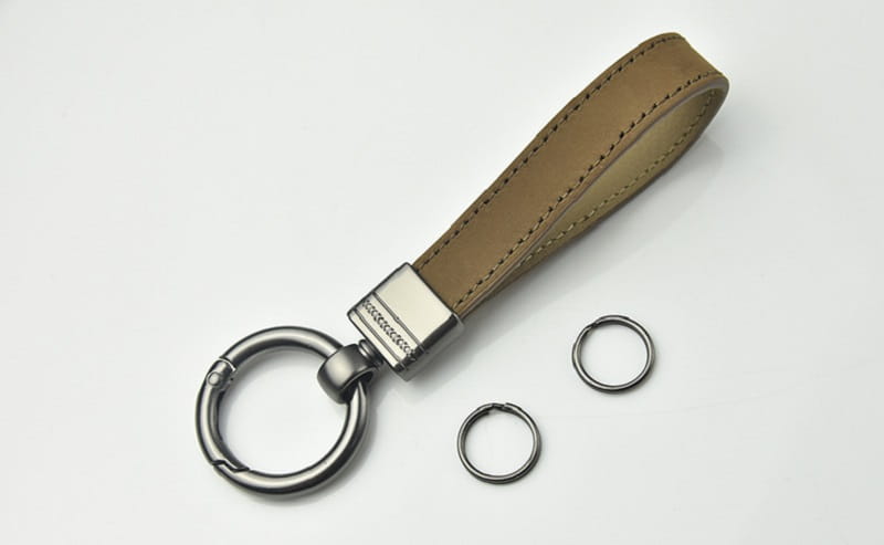 Tan leather key fob with a silver metal clasp and carabiner from a leather keychains set featuring multicolor metal clasps.