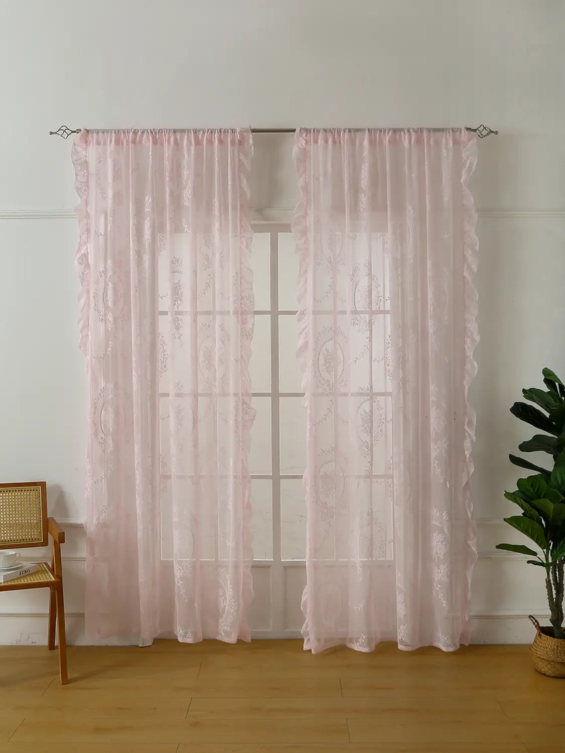 Cortinas de encaje rosa delicadas con tejido semitransparente de intrincado diseño y bordes fruncidos que cuelgan con elegancia de un bolsillo para barra de soporte circular para espejo decorativa.