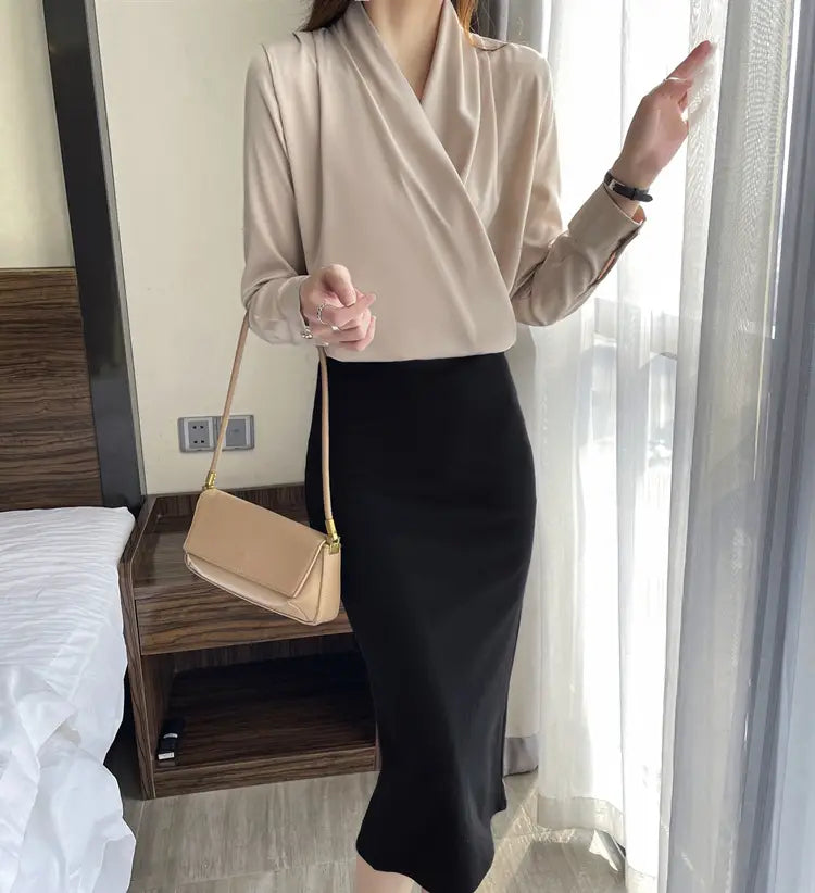 構造的な長方形のシルエットとゴールドトーンの金具が、女性用Vネックサテンのロングスリーブトップを引き立てるベージュのクロスボディバッグ。