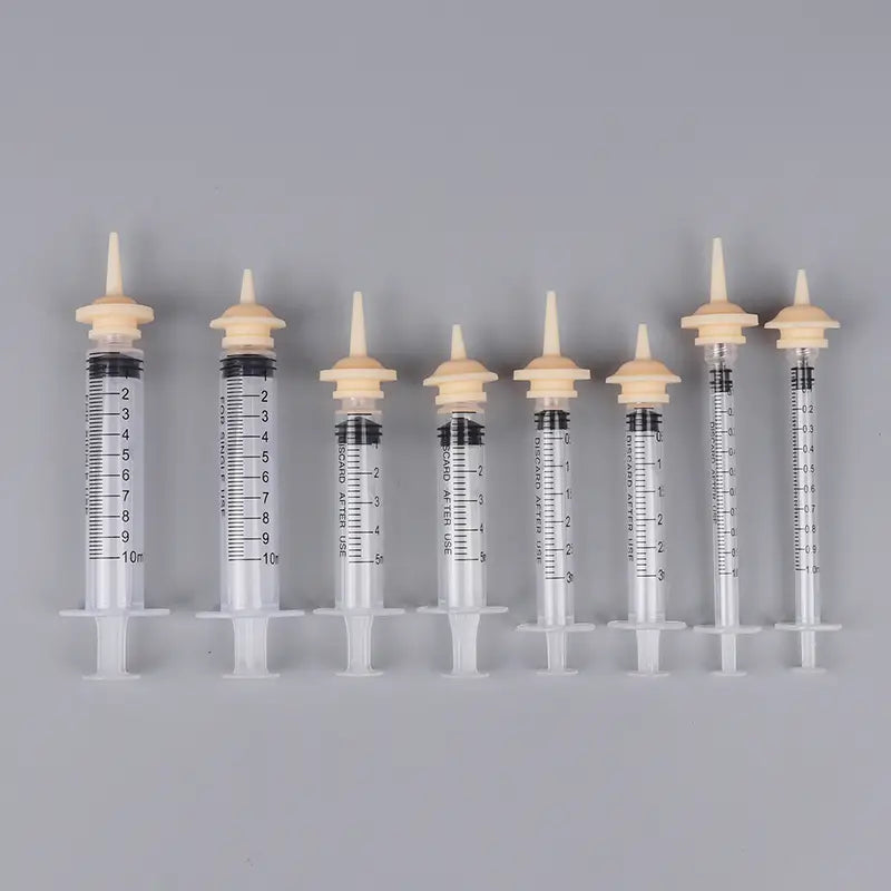 clear plastic pet oral syringes with beige caps and black measurement markings featuring silicone nipples for feeding.