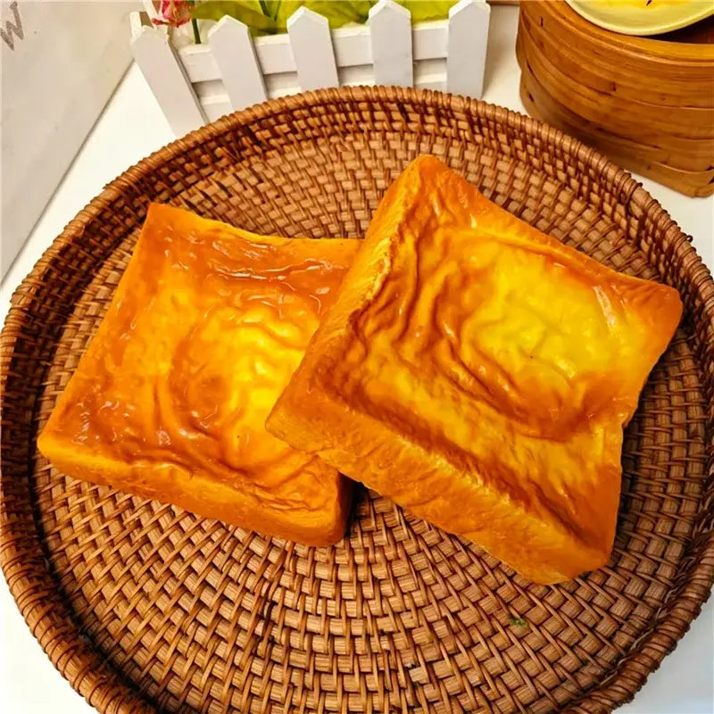 goldbraunes, quadratisches Hundebrot – langsam aufsteigendes, weiches Knetspielzeug mit glänzender Oberfläche und sichtbarer Krustentextur.