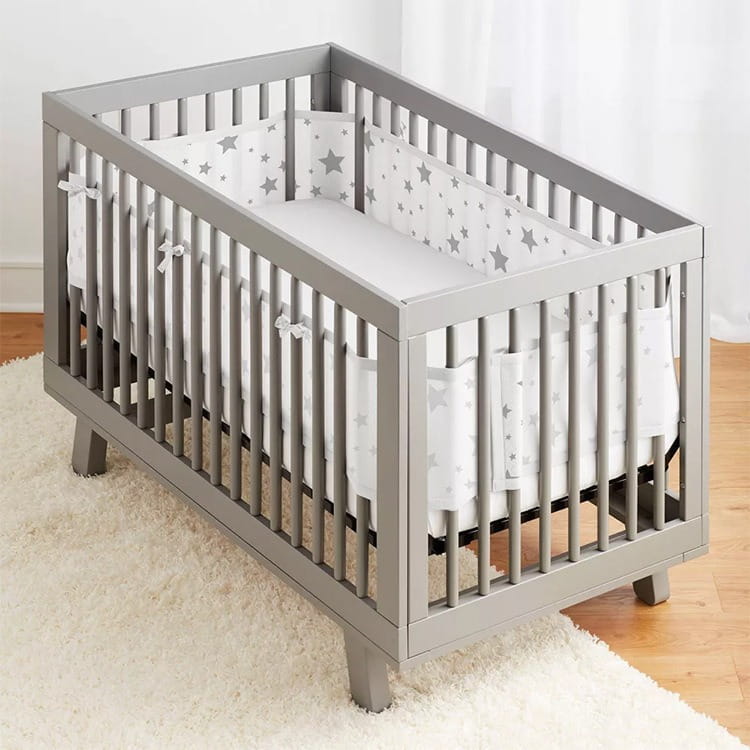 Graues Holz-Kinderbett mit atmungsaktiven Mesh-Seitenteilen und weißer Bettwäsche mit Sternmuster aus der Teddy-Bären-Bettwäsche-Kollektion.