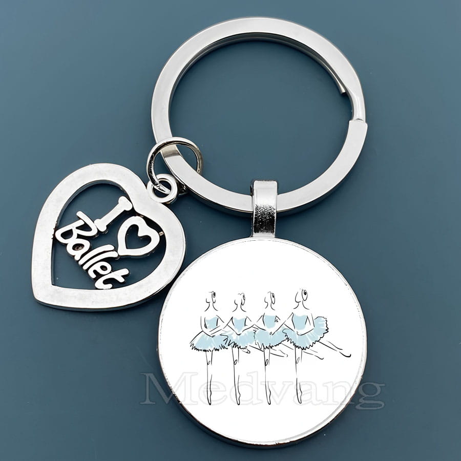 銀色のバレエキーチェーンで、ハート形のチャームに「I heart ballet」があり、淡い水色のチュチュを着た3人のバレリーナを描いた円形のガラスドームペンダント。ダンサーギフトに最適。