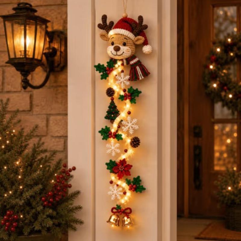 Decoración navideña colgante de reno tejida a crochet con un sombrero rojo tipo Santa, copos de nieve verde y blanco, piñas, hojas de acebo, árboles en miniatura y campanas doradas sobre una guirnalda iluminada, para decoración iluminada de pared de Navidad.