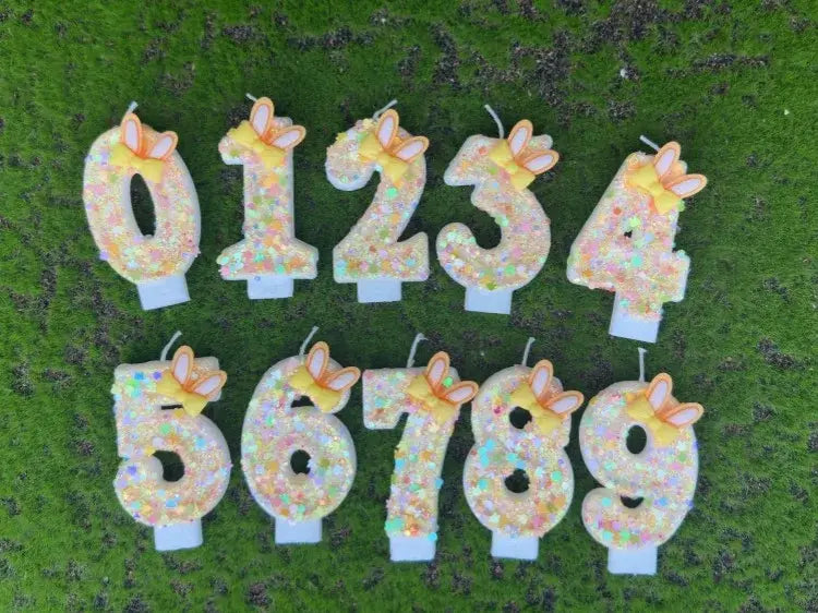Set of ten glittery pastel-colored number birthday candles with yellow bunny ears and white bases.