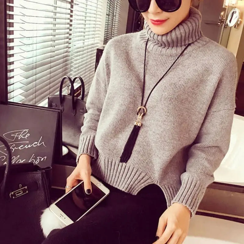 Pull col roulé gris à poignets et ourlet côtelés, associé à un long collier à gland en alliage de zinc présentant un type de chaîne durable pour les femmes.