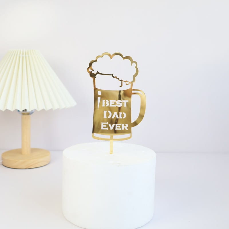 Gold-colored metallic beer mug cake topper with best dad ever engraved in white lettering designed for Father’s Day acrylic cake topper super dad.