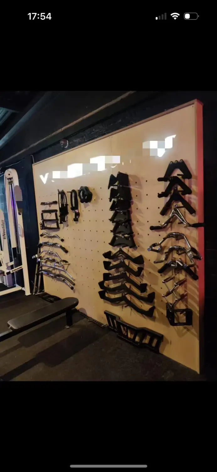 black leather bowhunting gear displayed on a pegboard wall alongside a commercial stair climber machine cardio stepmill for fitness use