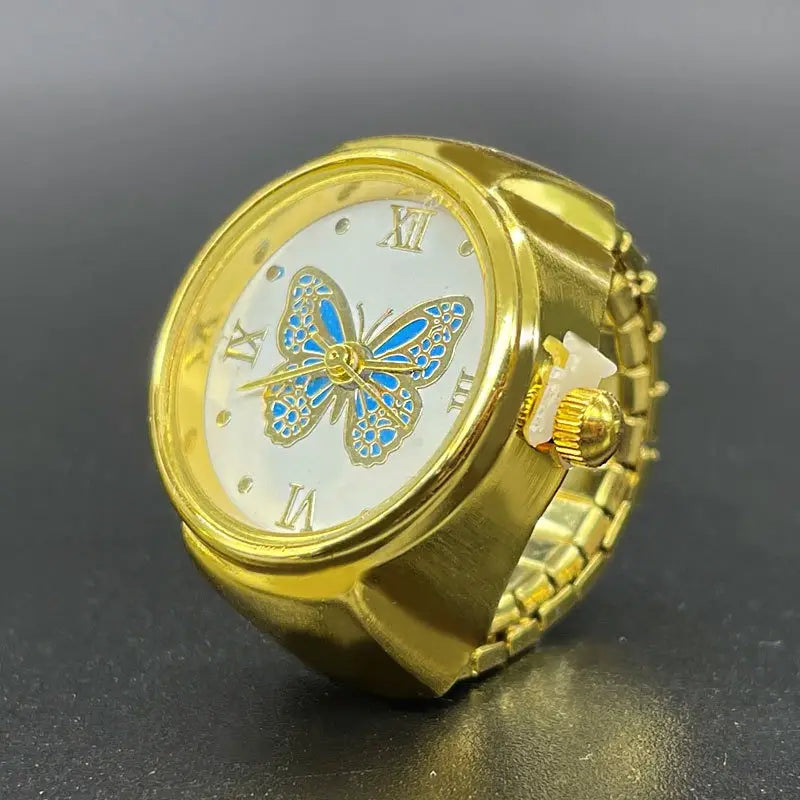 Gold butterfly watch ring stainless steel jewelry featuring a gold-colored band with a white face, roman numerals, and an ornate blue butterfly design.