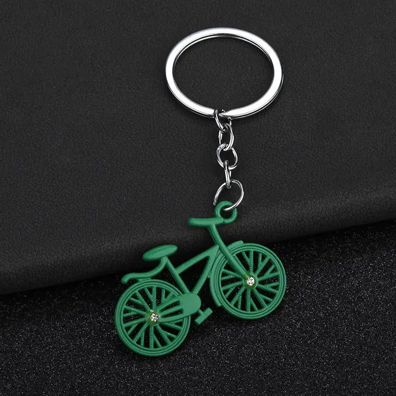 Green bicycle-shaped keychain charm set with silver metal ring and chain featuring clear rhinestones on the wheel hubs.