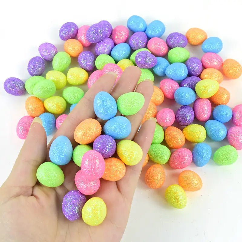 A hand holds colorful glitter Easter foam eggs in vibrant pink blue green yellow and purple for party decor DIY in an 80 piece set.