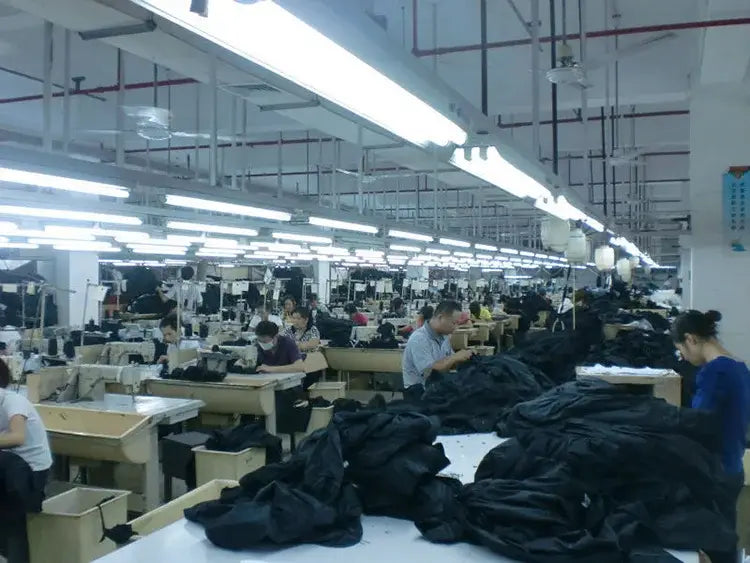 black fabric piles on a white worktable in a garment factory for women double-breasted trench coat casual windbreaker production